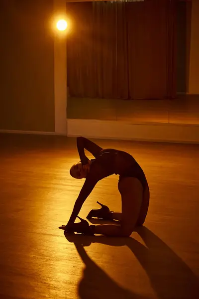 Anmutige Frau wird vom Umgebungslicht beleuchtet, während sie gegen den Spiegel tanzt — Stockfoto