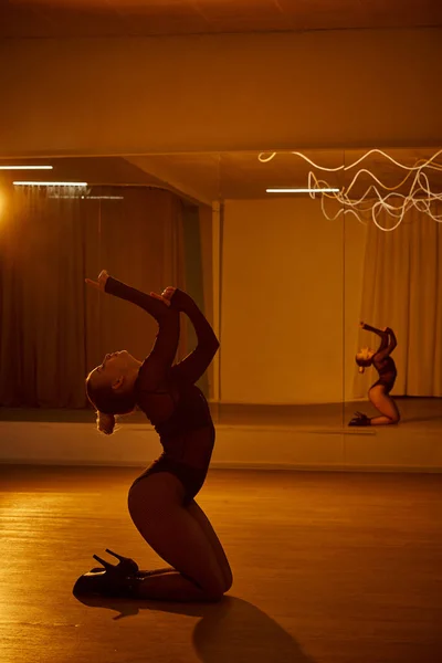 Женская изящная форма освещена окружающим светом, женщина танцует у зеркала — стоковое фото