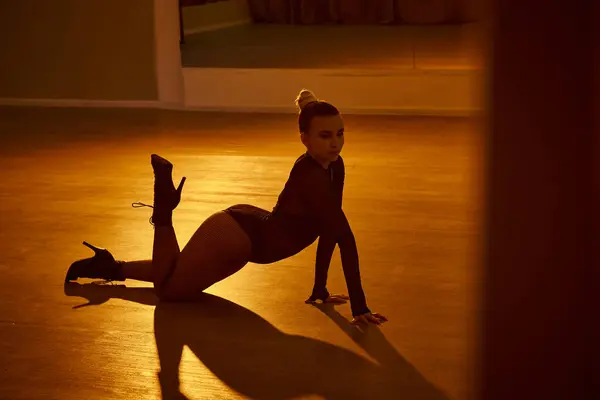 Уравновешенная женщина демонстрирует изящество и силу в танцевальной позе, ее высокие каблуки крепко посажены на пол — стоковое фото
