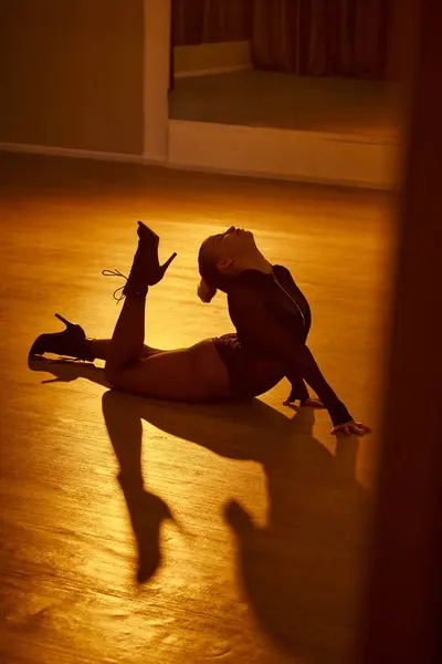 Гостра жінка демонструє витонченість в позі танцю, її високі підбори міцно посаджені на підлозі — стокове фото