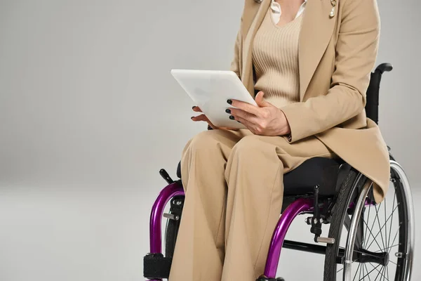 Vue recadrée de la femme handicapée en fauteuil roulant dans des vêtements élégants tenant tablette, déficience — Photo de stock