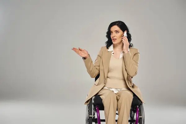 Confiant belle femme handicapée en costume pastel en fauteuil roulant parler par téléphone mobile — Photo de stock