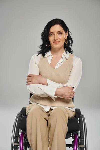 Весела гарно виглядає впевнена жінка з інвалідністю сидячи в інвалідному візку і посміхаючись на камеру — стокове фото