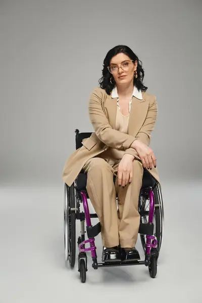Bella donna disabile con i capelli ondulati in abito pastello con occhiali in sedia a rotelle guardando la fotocamera — Foto stock