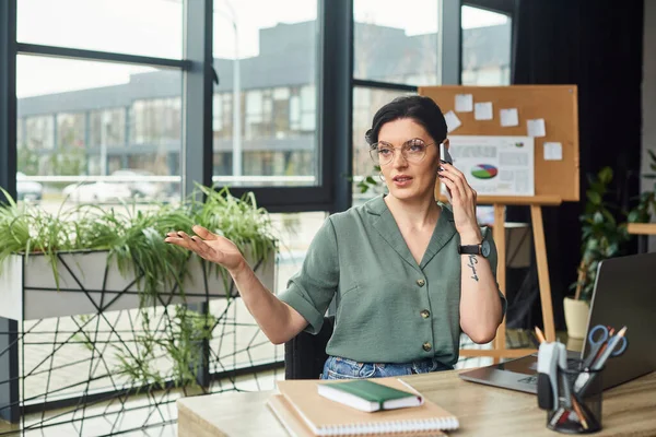 Good looking confident disabled businesswoman in wheelchair talking by phone in her office — Stock Photo