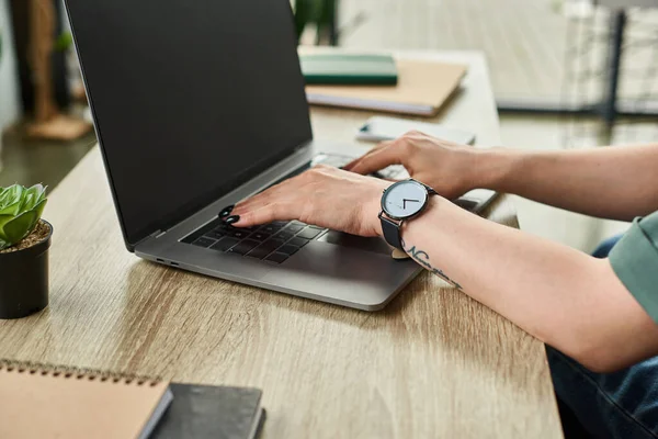 Vue recadrée de femme d'affaires dédiée avec tatouage et montre-bracelet travaillant sur son ordinateur portable au bureau — Photo de stock