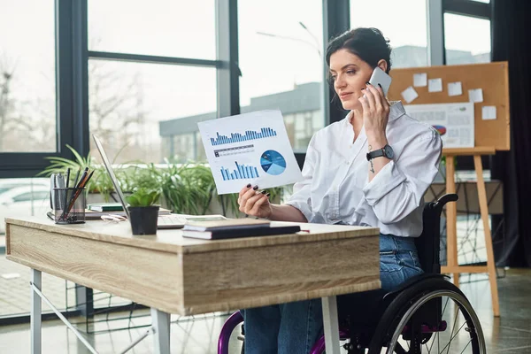 Schöne behinderte Geschäftsfrau im Rollstuhl diskutiert ihre Grafiken per Smartphone — Stockfoto