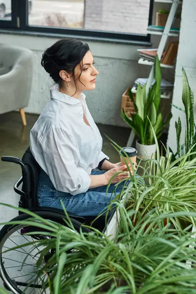 Attrayant femme d'affaires en fauteuil roulant en tenue décontractée tenant café alors qu'à son bureau — Photo de stock