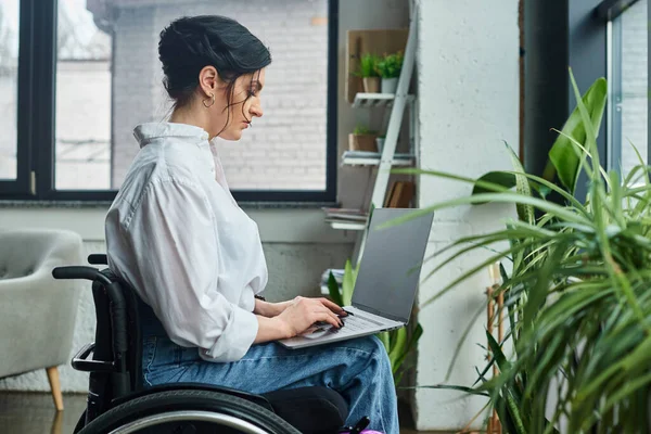 Bella donna d'affari dedicata in abbigliamento casual in sedia a rotelle che tiene il suo computer portatile in ufficio — Foto stock
