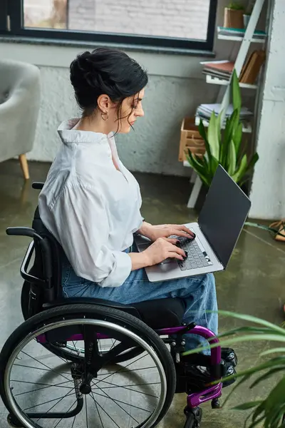 Attentif belle femme d'affaires avec handicap en fauteuil roulant regardant ordinateur portable tout en travaillant dur — Photo de stock