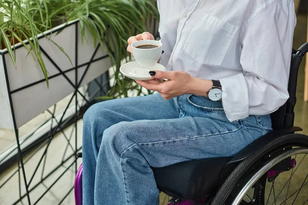 Vue recadrée d'une femme d'affaires à mobilité réduite en fauteuil roulant tenant une tasse de café au bureau — Photo de stock