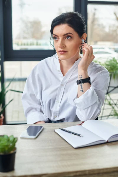 Good looking disabled businesswoman with headphones sitting in wheelchair and looking away — Stock Photo