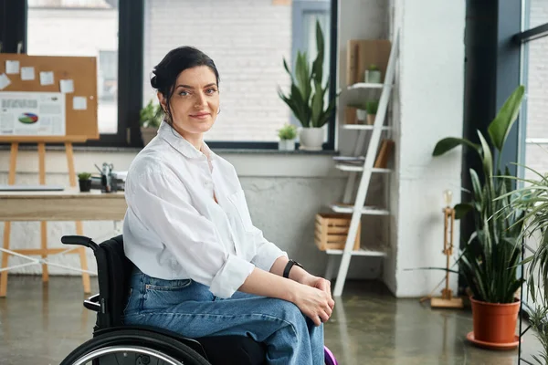 Красивая веселая женщина-инвалид в стильном наряде сидит в инвалидном кресле и улыбается в камеру — стоковое фото
