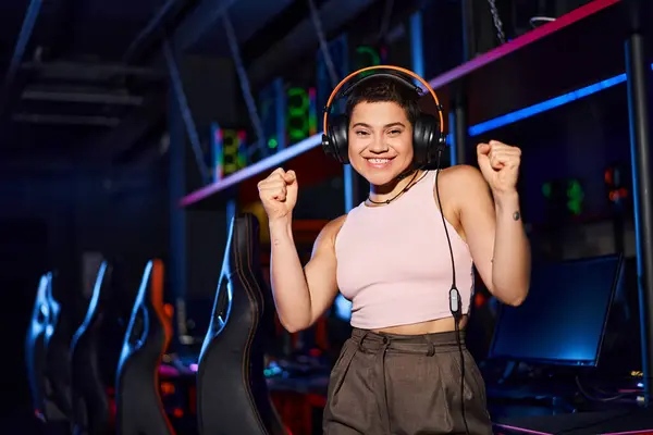 Tattooed and happy young woman wearing headphones and holding her fists up, positivity and dance — Stock Photo