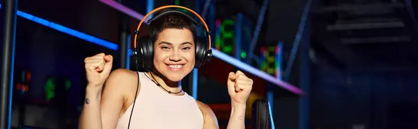 Tattooed and happy young woman wearing headphones and holding her fists up, horizontal banner — Stock Photo