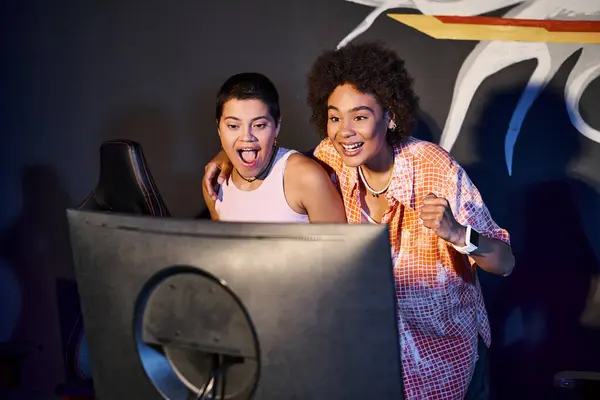 Amigos interraciales y felices mirando el monitor de la computadora y celebrando la victoria, cybersport - foto de stock