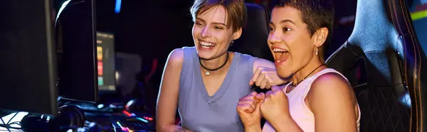 Excited women with tattoos concentrating on a cybersport game in computer club, female gamers banner — Stock Photo