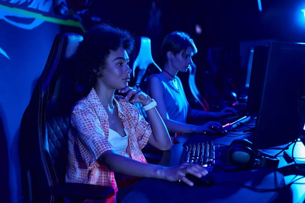 Focus on serious african american woman gaming intensely in a blue-lit room, cybersport concept — Stock Photo