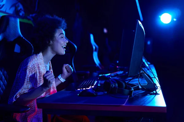 Focus on happy african american woman winning game in a blue-lit room, cybersport concept — Stock Photo