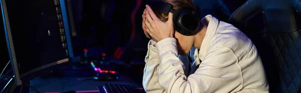 Upset gamer in headphones with hands on face after a losing cybersport match, disappointment banner — Stock Photo