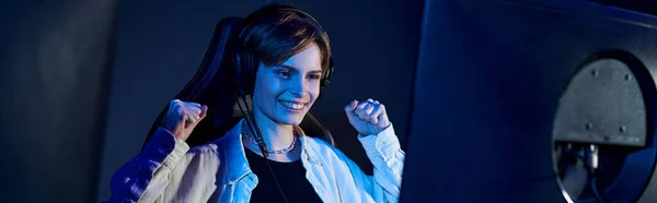 Happy short-haired woman looking at computer in a blue-lit room, cybersport and gaming banner — Stock Photo