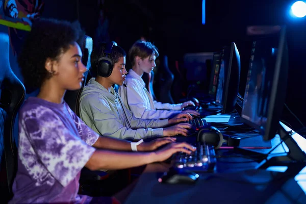 Diverse interracial women zoomers engaged in cybersport games, using computers and headphones — Stock Photo