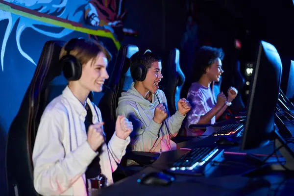 Схвильовані міжрасові жіночі зуми, що займаються кіберспортивними іграми, використовуючи комп'ютери та навушники — стокове фото