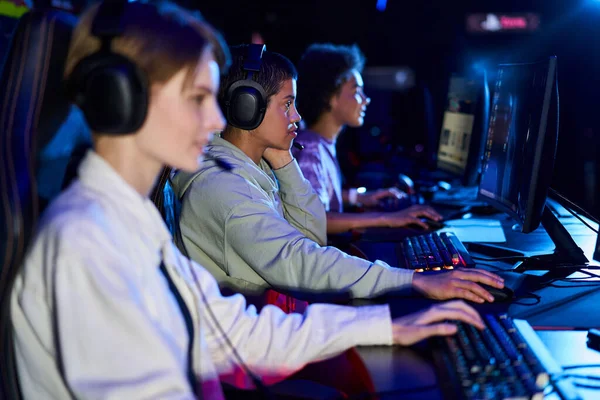 Diversas y jóvenes mujeres interracial que participan en juegos de ciberdeporte, utilizando computadoras y auriculares - foto de stock