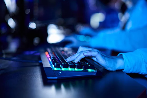 Se concentrer sur les mains féminines recadrées tapant sur le clavier d'ordinateur avec éclairage, pièce avec lumière bleue — Photo de stock