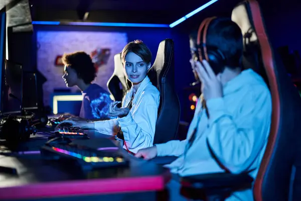 Fokus auf lächelnde Frau mit kurzen Haaren, die Spielern nahe Monitor Ratschläge zur Spielstrategie gibt — Stockfoto