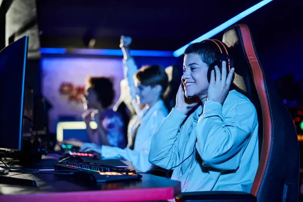 Focus on cheerful young woman winning game next to diverse female friends, cybersport gamers — Stock Photo