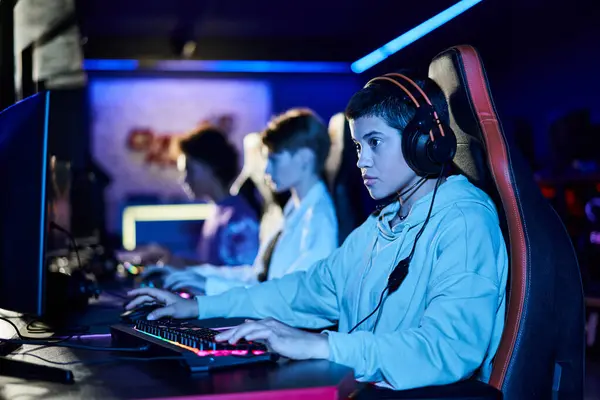 Зосередитися на концентрованій молодій жінці, граючи в гру поруч з різноманітними друзями, кіберспорт геймерами — стокове фото