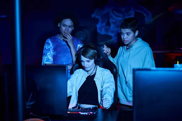 Young diverse female gamers looking at computer monitor while thinking on game strategy, cybersport — Stock Photo