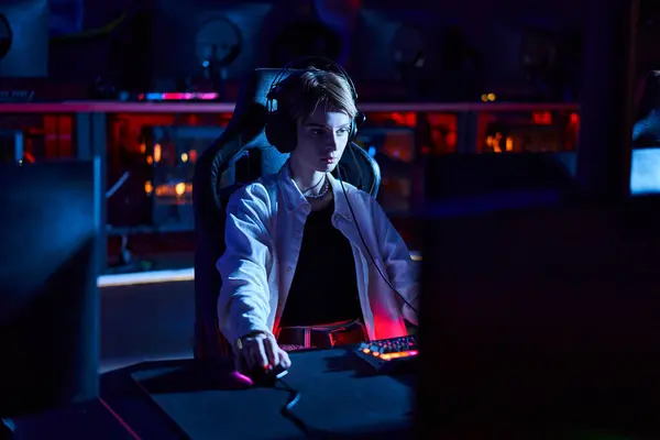 Young gamer in headphones looking at computer monitor while thinking on game strategy, cybersport — Stock Photo