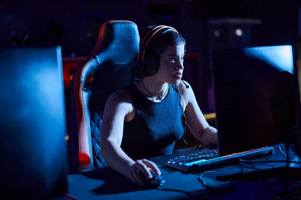 Сфокусированный геймер в наушниках смотрит на монитор компьютера, размышляя о стратегии игры, киберспорте — стоковое фото