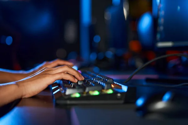 Обрізані жіночі руки, що друкуються на клавіатурі комп'ютера з підсвічуванням, жінка в кімнаті з синім світлом — стокове фото