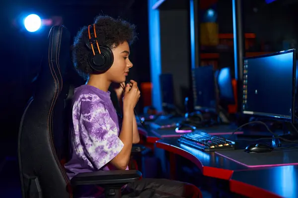 Lockige Afroamerikanerin mit Kopfhörer berührt Mikrofon beim Computerspiel — Stockfoto