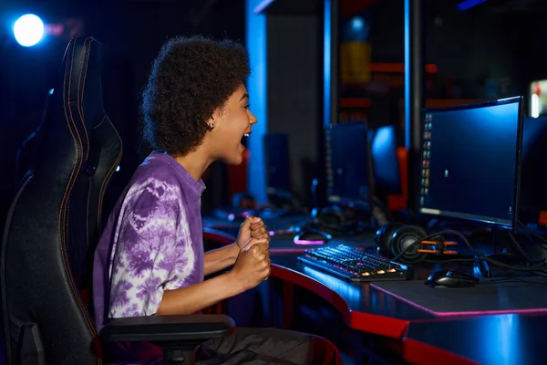 Збуджений афроамериканський гравець кричить від радості, вигравши комп'ютерну гру, кіберспорт — стокове фото