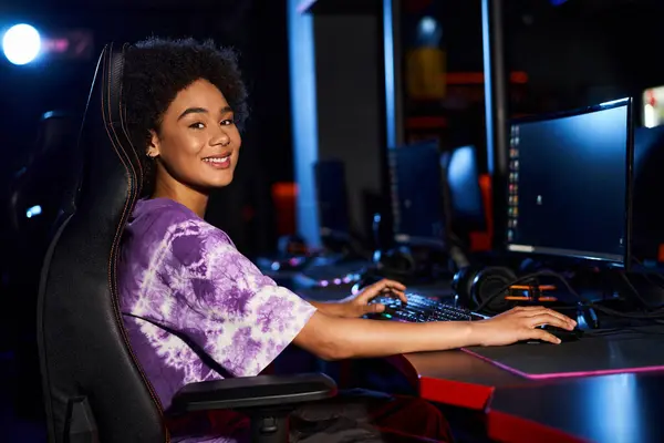 Cheerful african american woman sitting in gaming chair and looking at camera, cybersport — Stock Photo