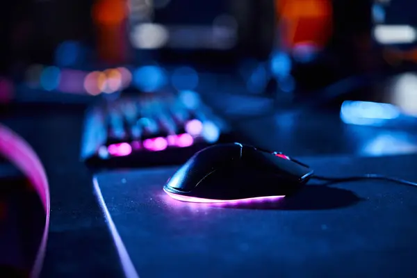 Крупный план подсвеченной компьютерной мыши рядом с клавиатурой компьютера, баннер игровых аксессуаров — стоковое фото