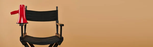 Chaise de réalisateur avec un mégaphone rouge sur fond beige, cinématographie et bannière de production — Photo de stock