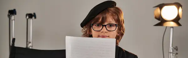 Niño bien vestido con gafas y guion de lectura de boina, niño como director de pancarta de cineasta - foto de stock