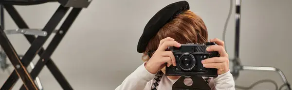 Niño en boina captura el momento en la cámara retro, bandera horizontal de joven fotógrafo - foto de stock