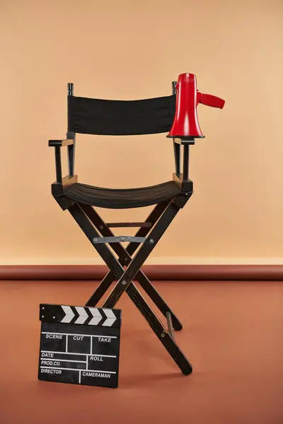 Diretor cadeira fica alto, adornado com um megafone e clapper board, conceito de cinematografia — Fotografia de Stock