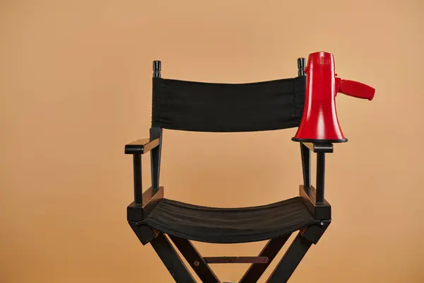 Une chaise de réalisateur avec un mégaphone rouge sur fond beige, la cinématographie et le concept de production — Photo de stock