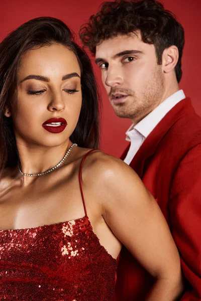 Portrait de belle jeune femme avec rouge à lèvres posant en robe brillante près de bel homme flou — Photo de stock