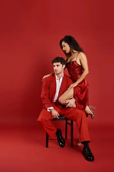 Sophistiquée jeune femme en robe sexy debout près de l'homme en tenue formelle sur fond rouge — Photo de stock