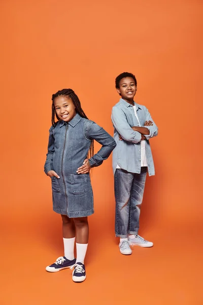Happy african american children in casual denim attire posing together on orange background — Stock Photo