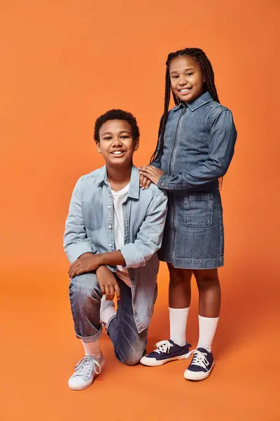 Happy preteen african american friends in casual outfits posing together on orange backdrop — Stock Photo