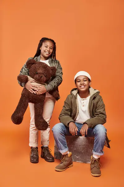 Allegro preadolescente bambini africani americani in posa con orsacchiotto e sorridente felicemente alla macchina fotografica — Foto stock
